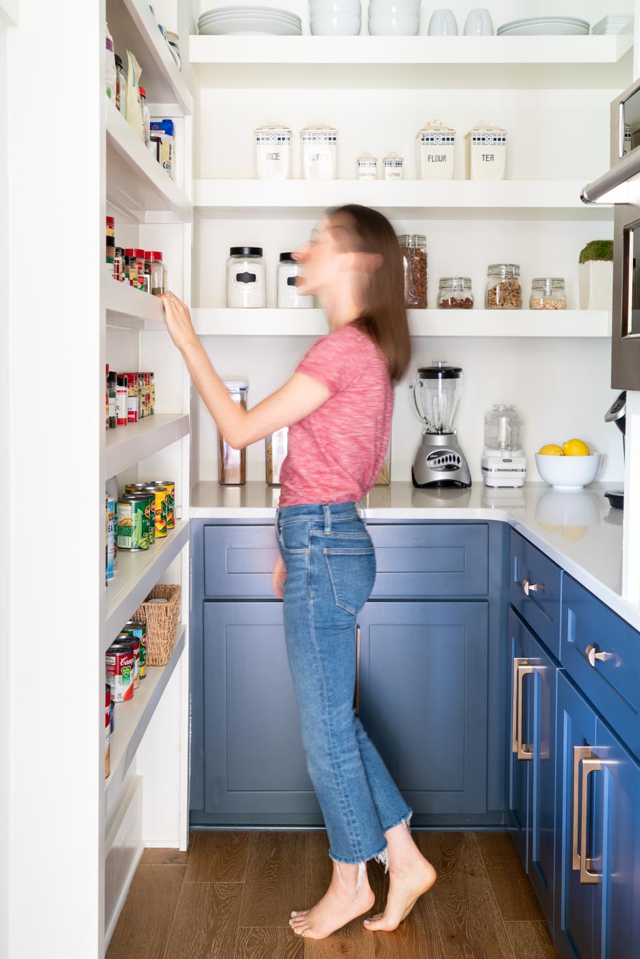 Woman looking through kitchen pantry shelves with spices on them 