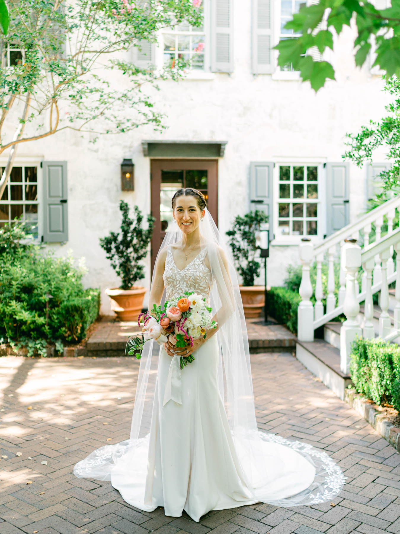 Bridal wearing a veil and holding a bouquet in a courtyard