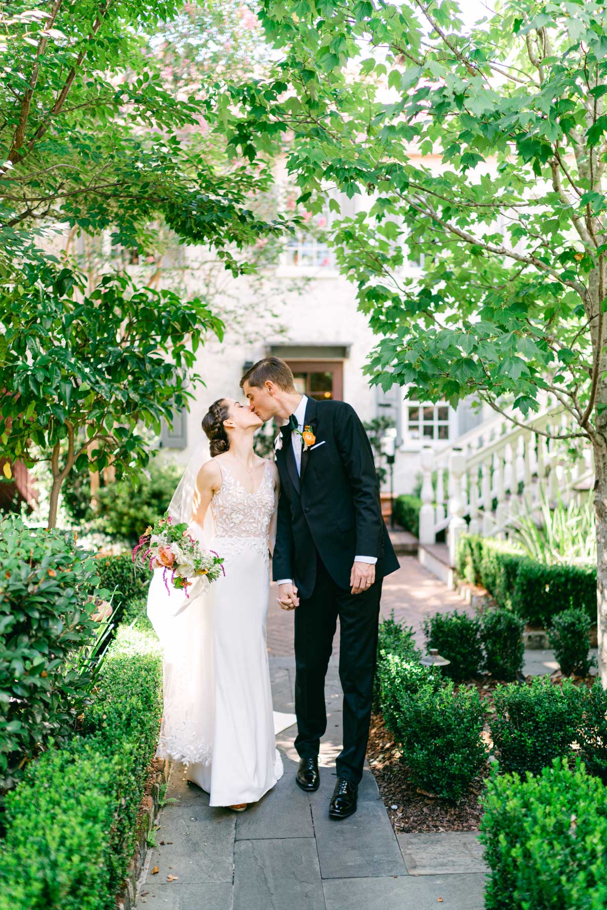 A bride and groom kissing and walking in a courtyard at Zero George hotel in Charleston, SC 