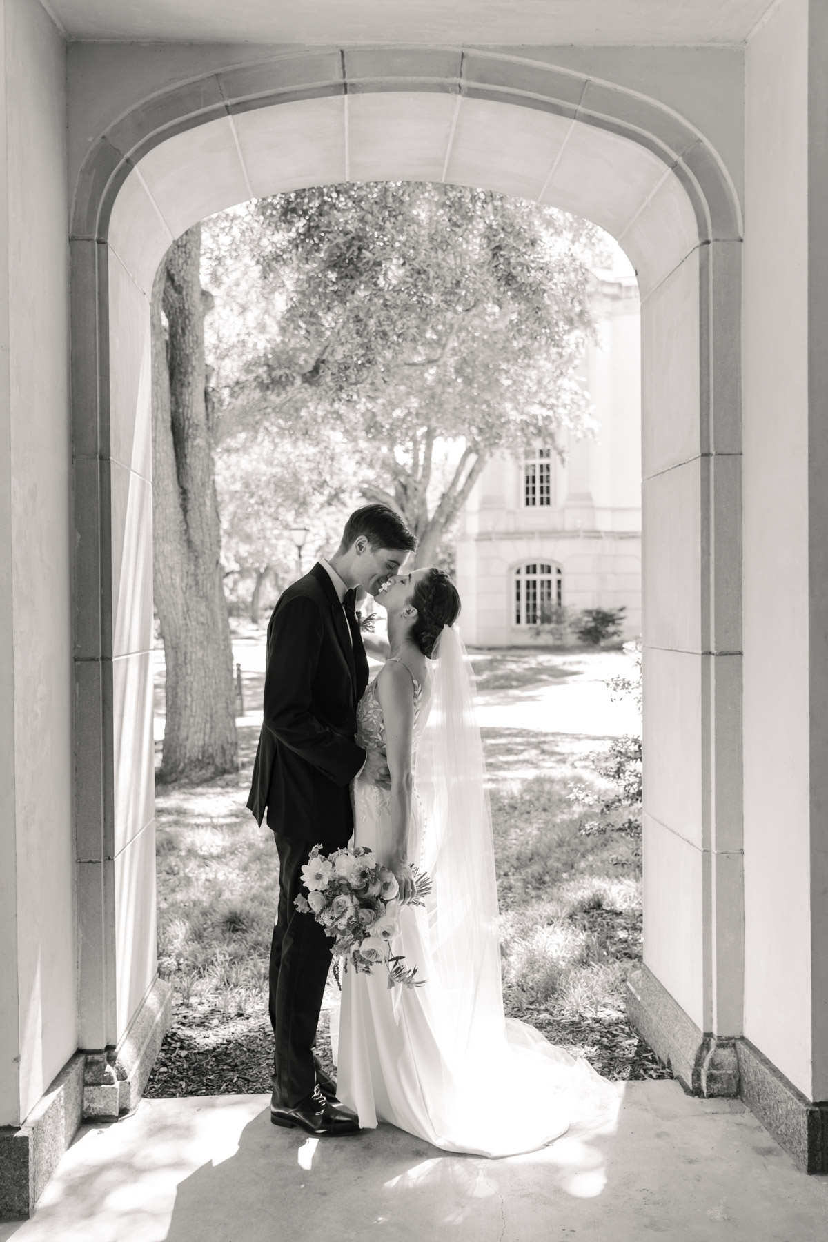 A bride and groom kissing under an archway at the Gaillard Center in Charleston, SC