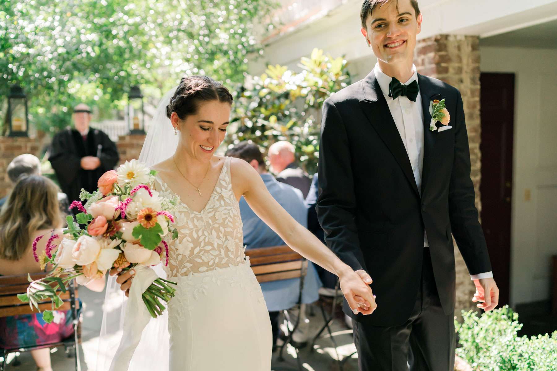 A bride and groom holding hands and smiling after they've walked down the aisle together