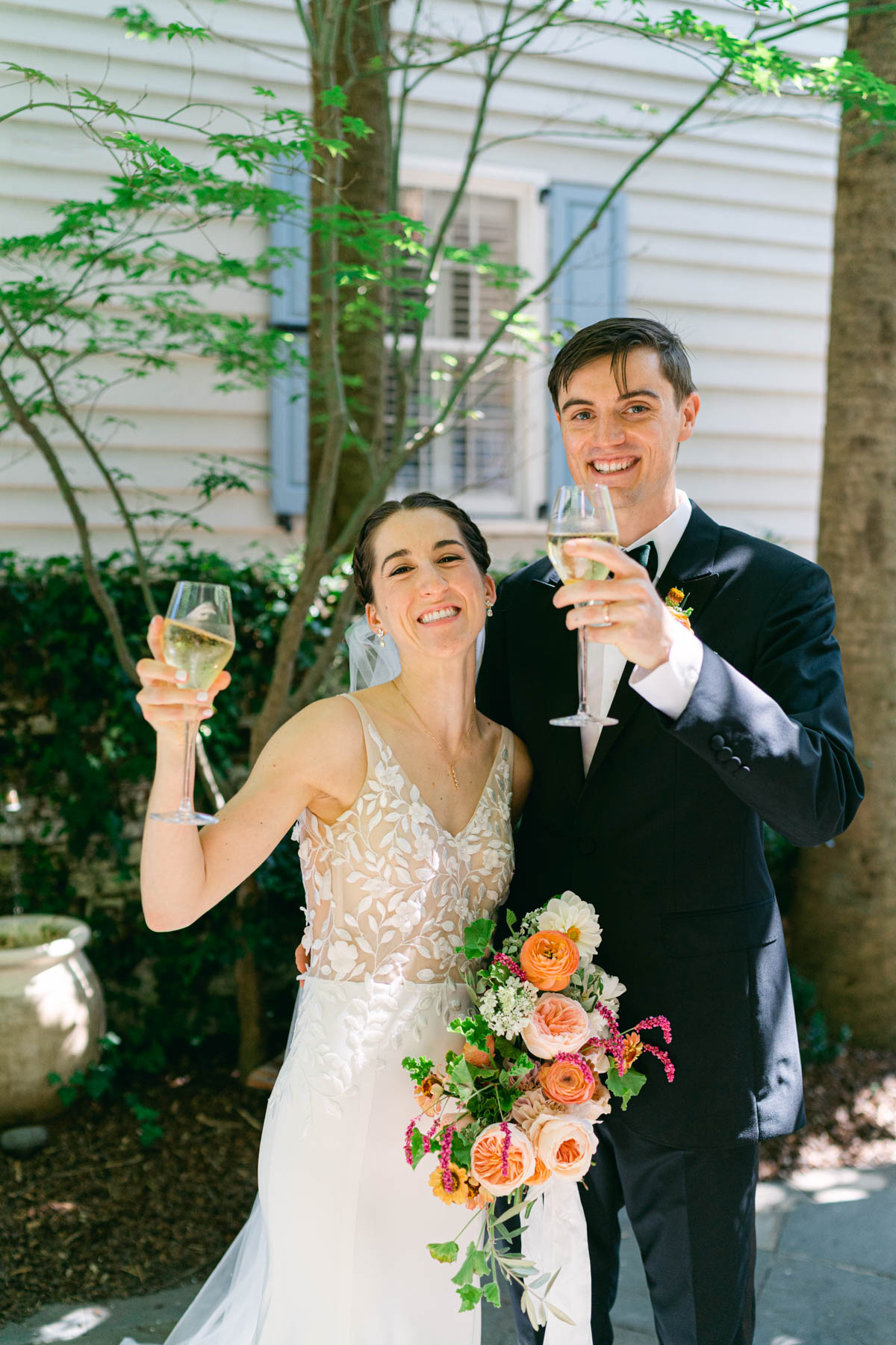 A bride and groom hold up champagne to cheers after they've just gotten married