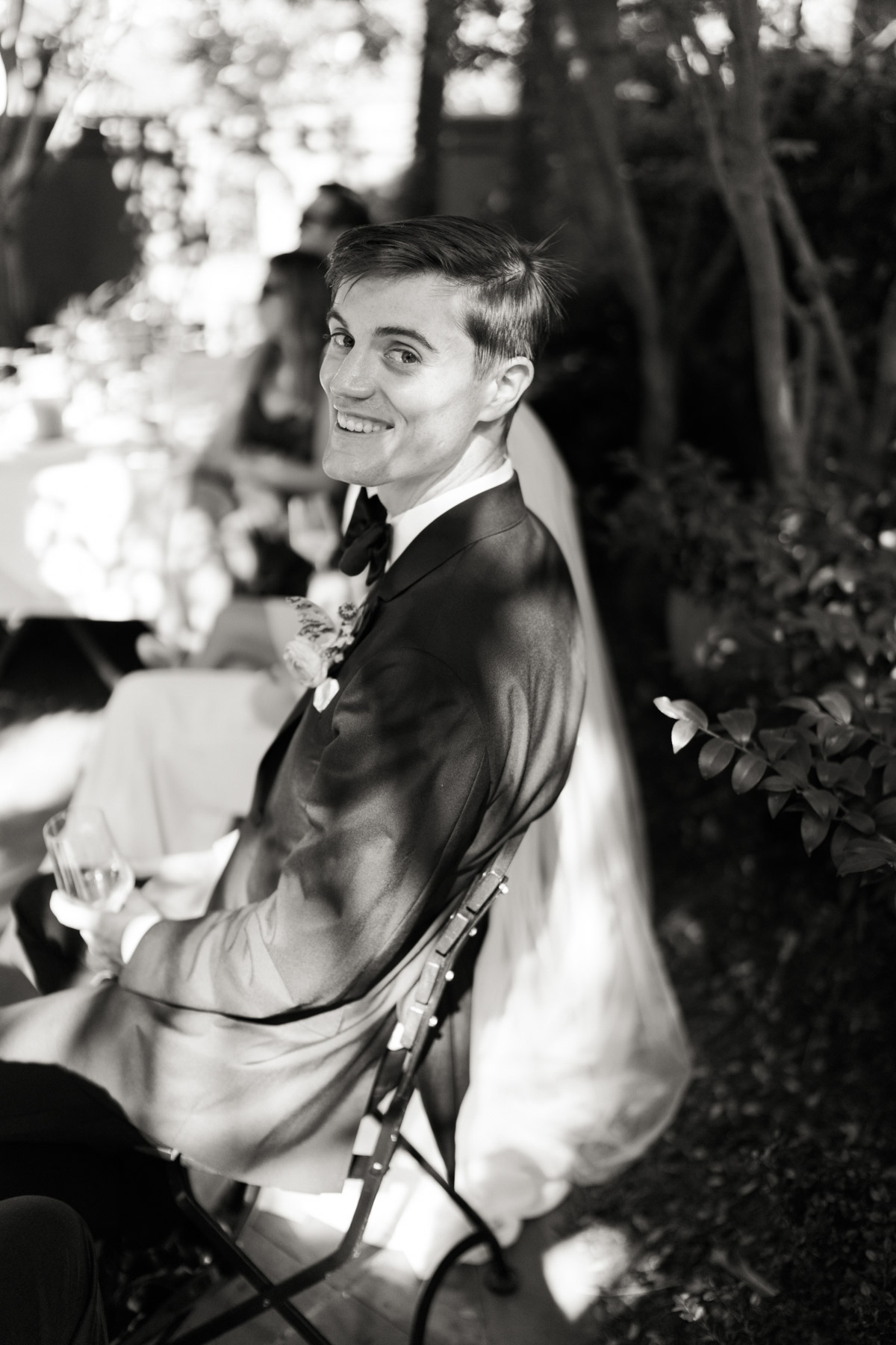 A groom smiles at the photographer in a candid moment during cocktail hour