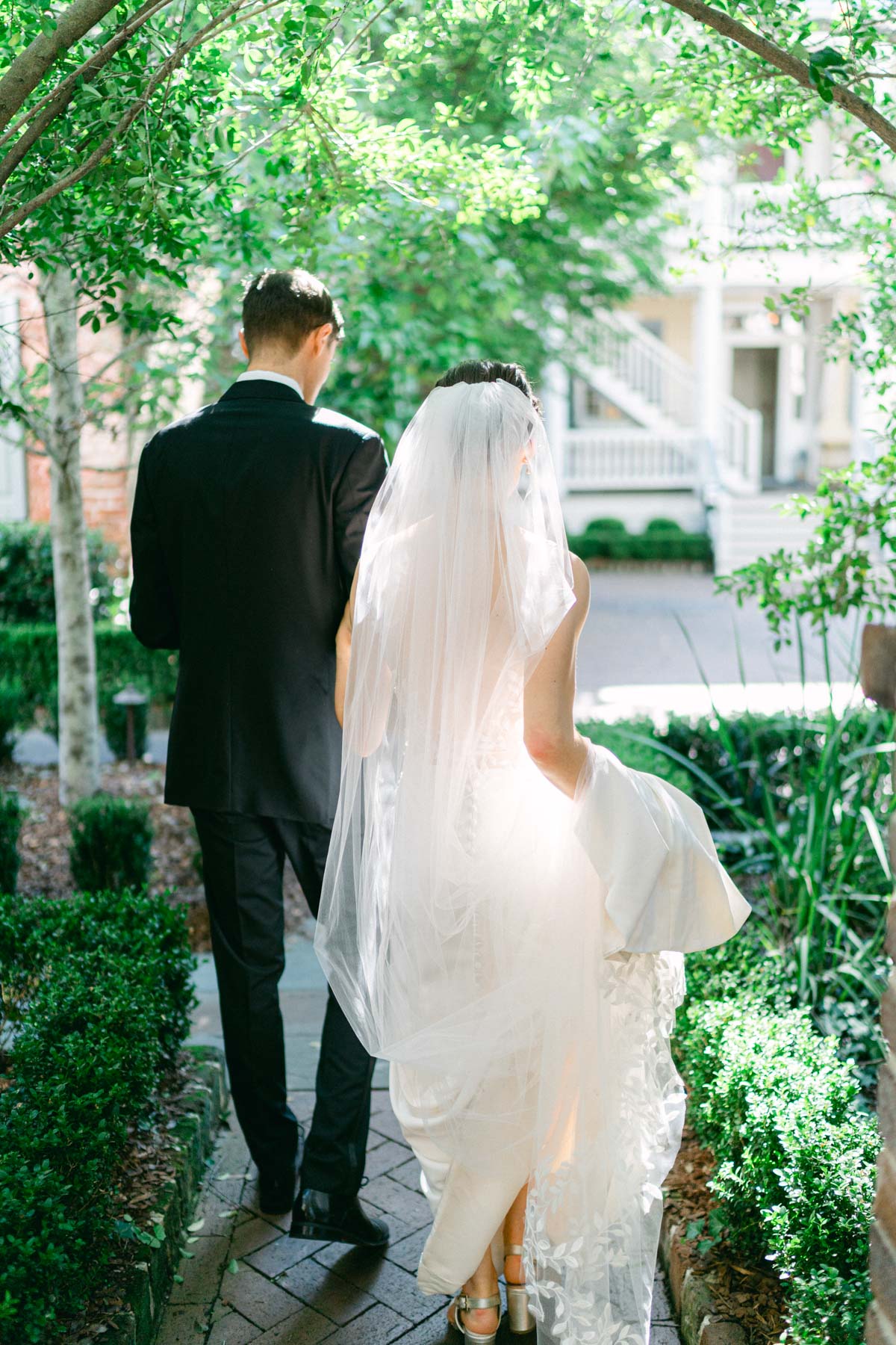 A bride and groom as they walk away into an intimate courtyard