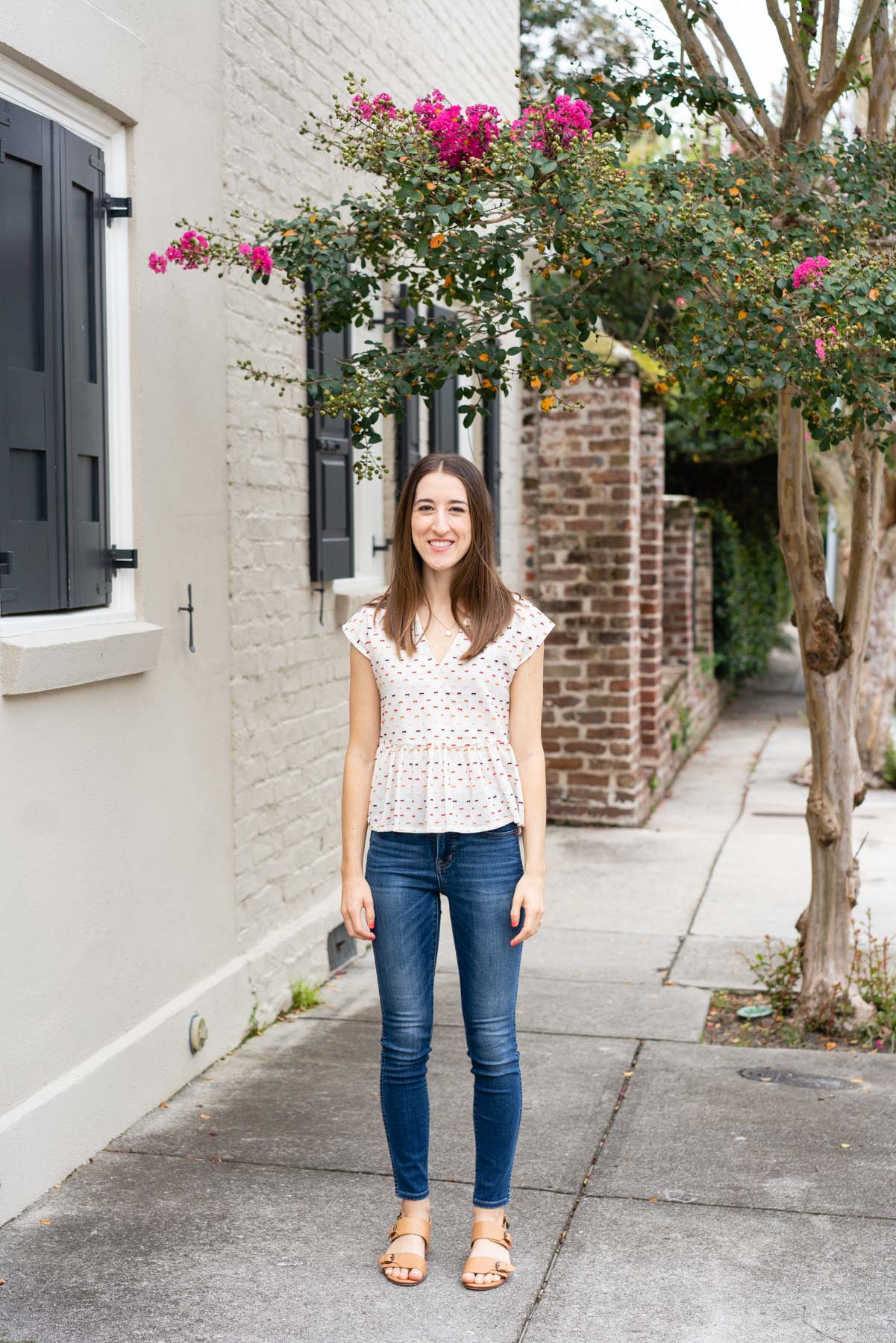 Woman in denim jeans and a white blouse standing on the sidewalk demonstrating how not to pose for a photoshoot