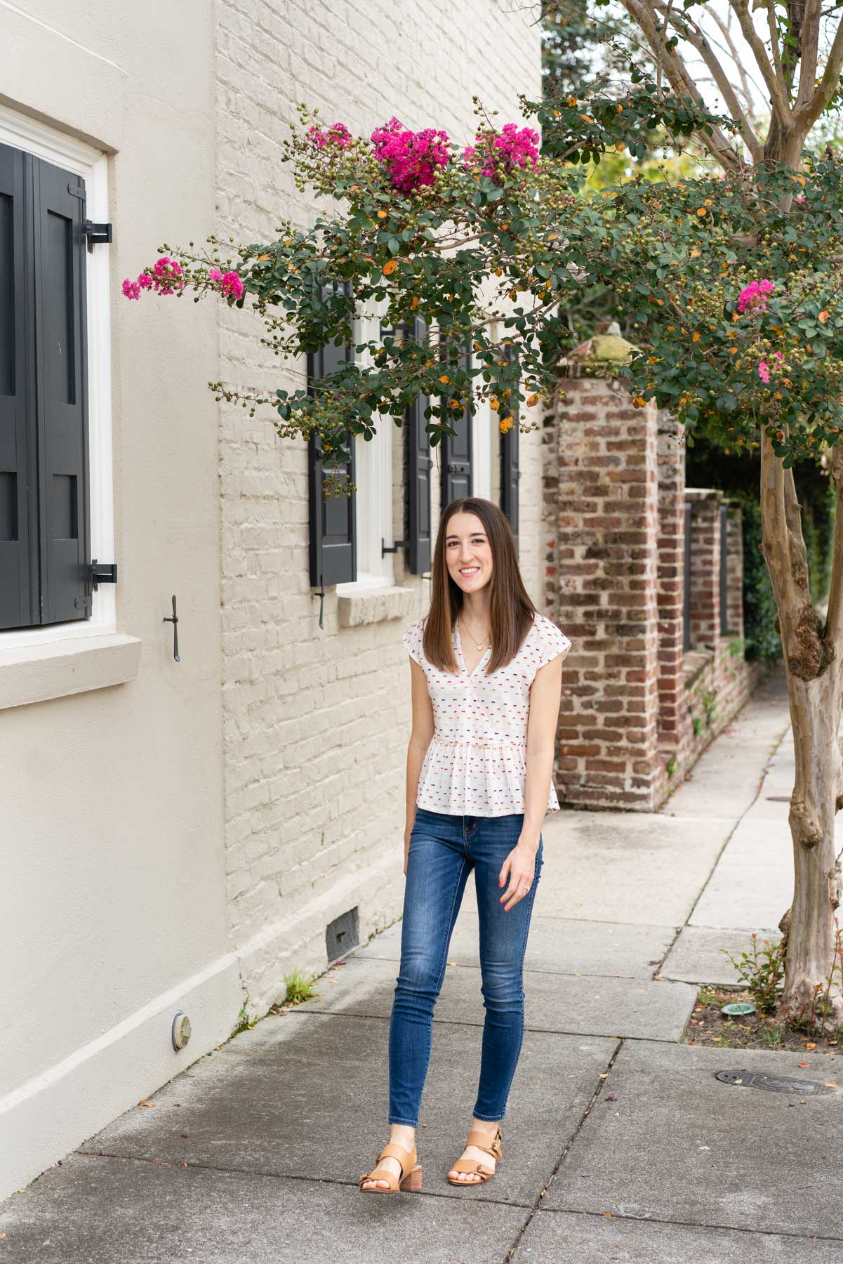 Woman in denim jeans and a white blouse walking down a sidewalk demonstrating how not to pose for a photoshoot by looking too stiff and robotic