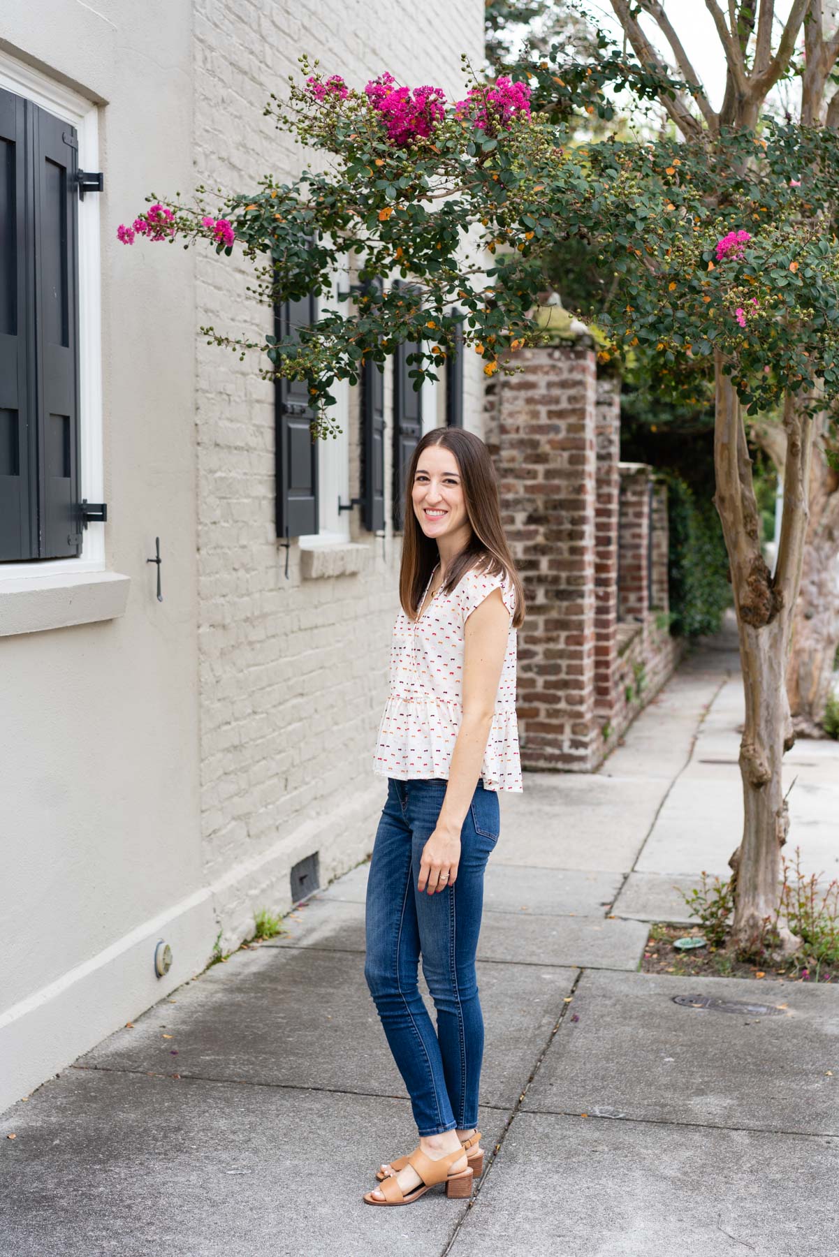 Woman in denim jeans and a white blouse standing on the sidewalk demonstrating how not to pose for a photoshoot