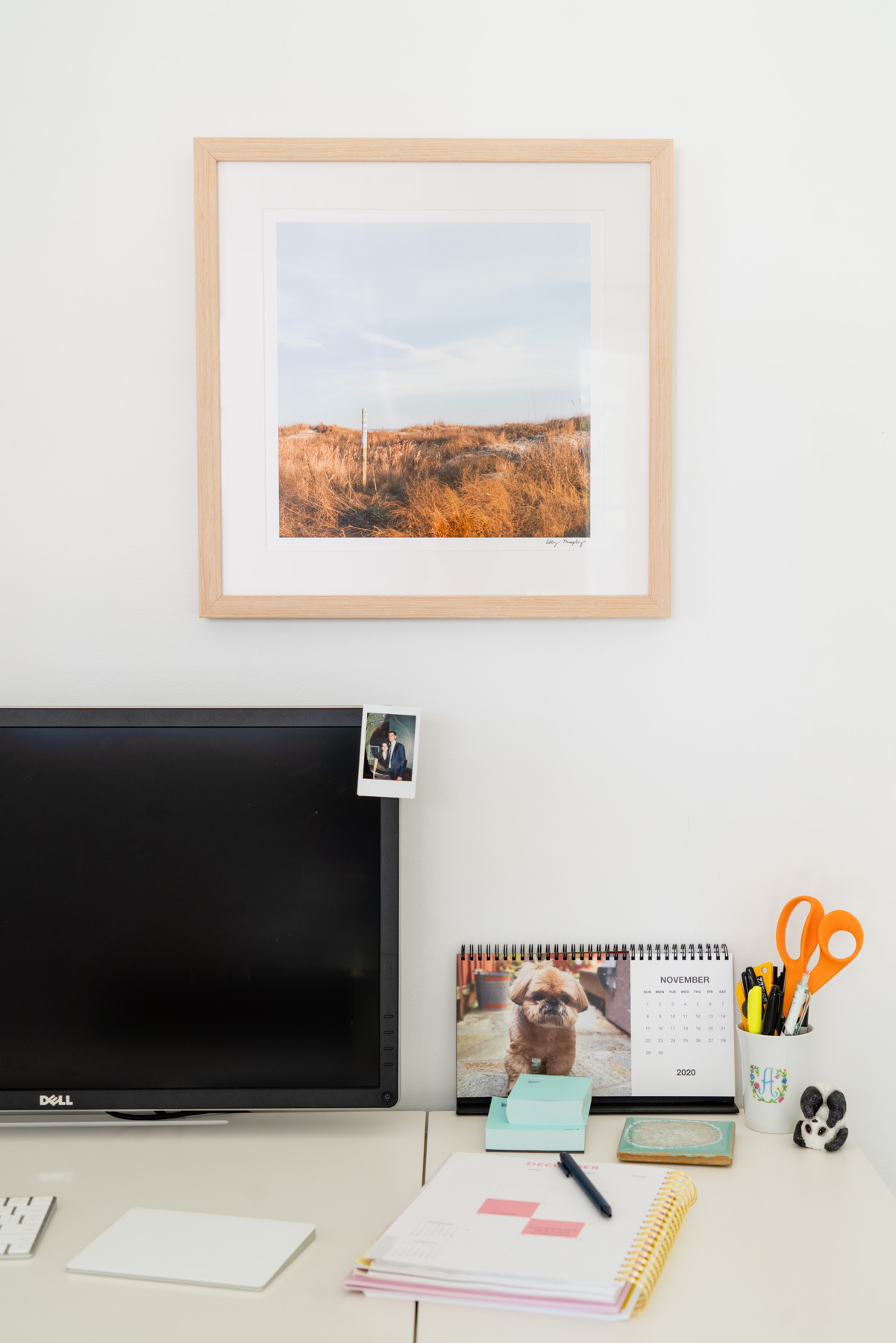 A framed photograph of a beach station in Sullivan's Island, South Carolina hanging on the wall above a desk