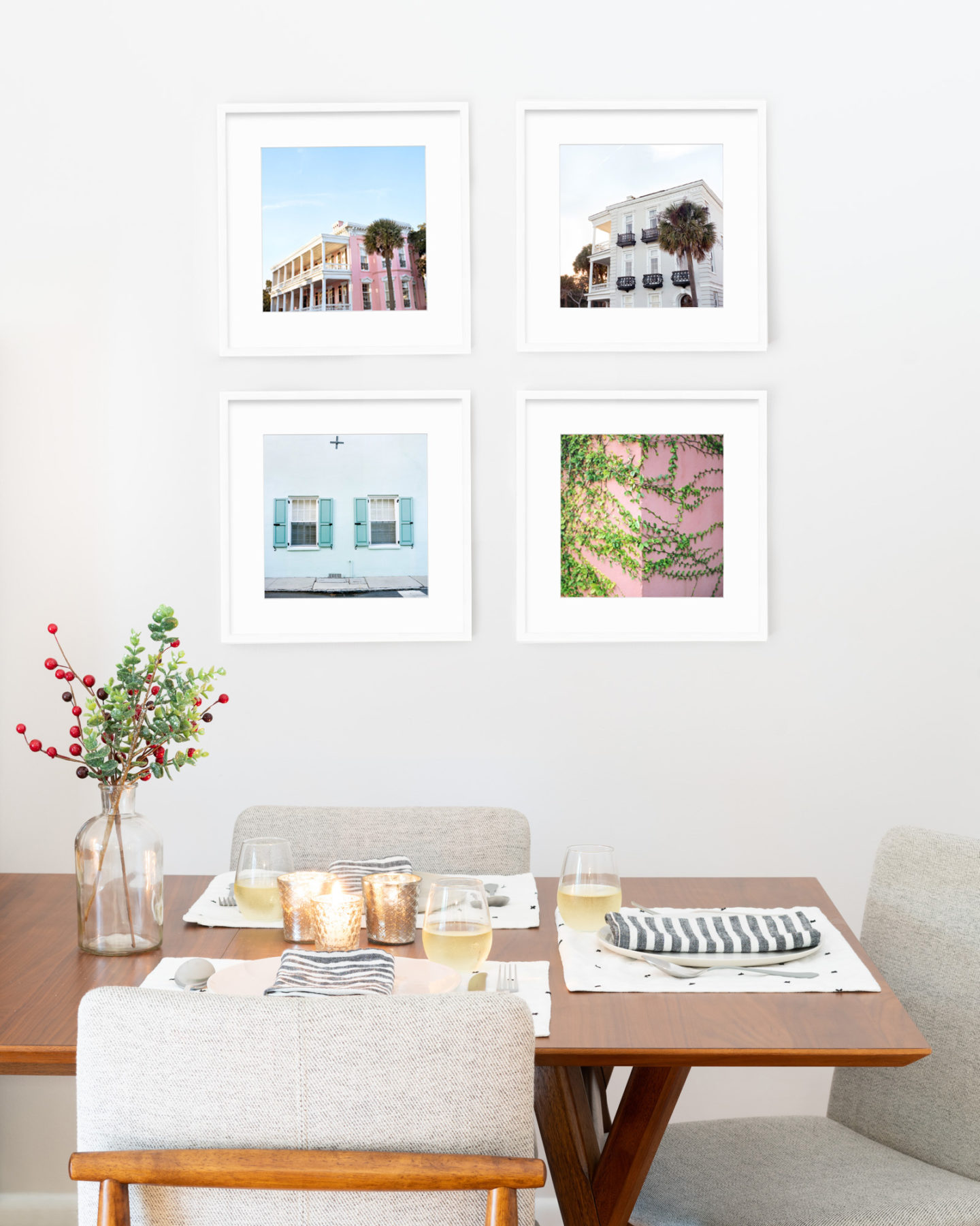 A gallery wall of colorful photographs of Charleston, South Carolina hanging over a mid-century modern dining room table.
