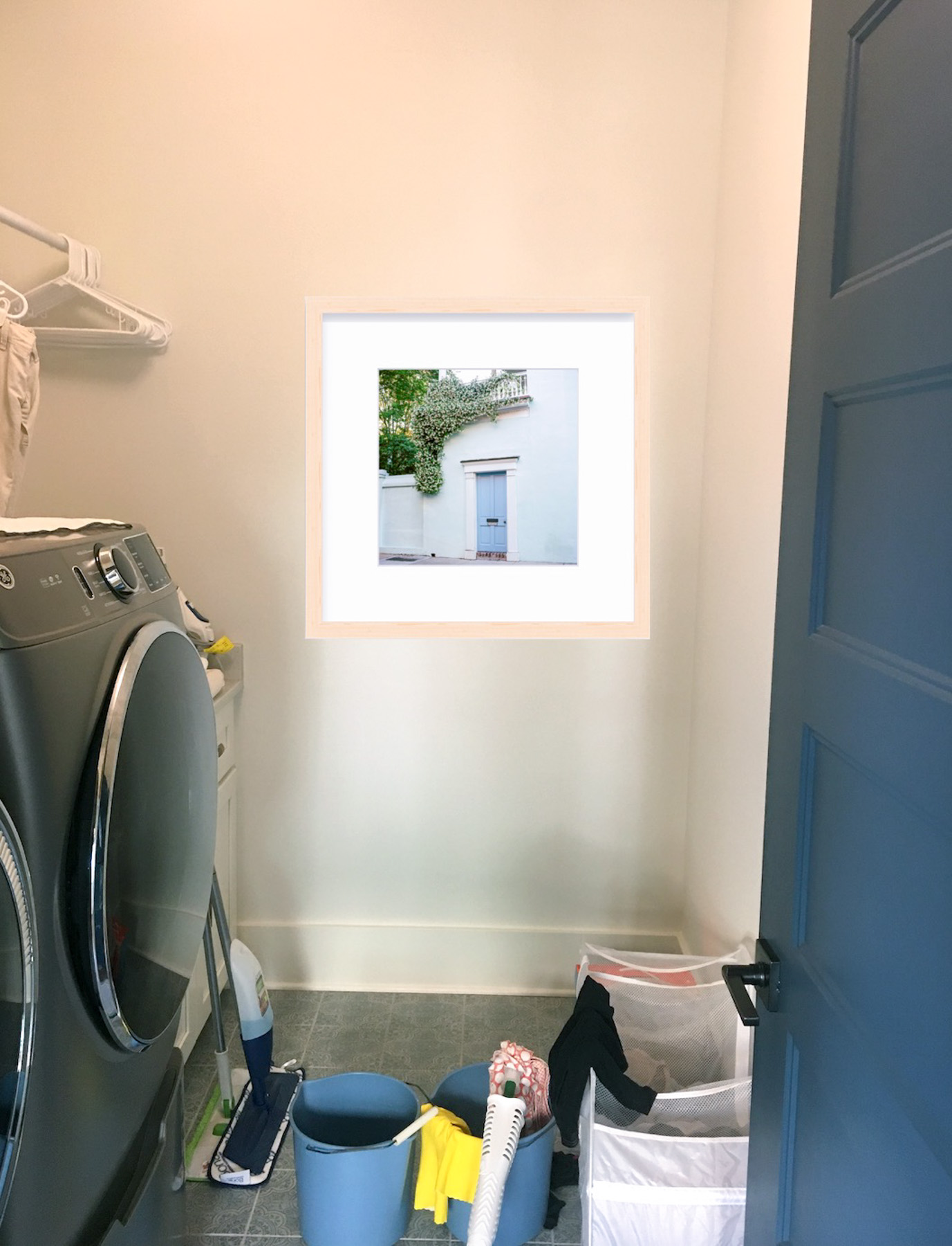 Before photo of a laundry room space with a Photoshopped photo in a frame. The photo was used as a preliminary design so the client could see what their space would look like with the frame on the wall. 