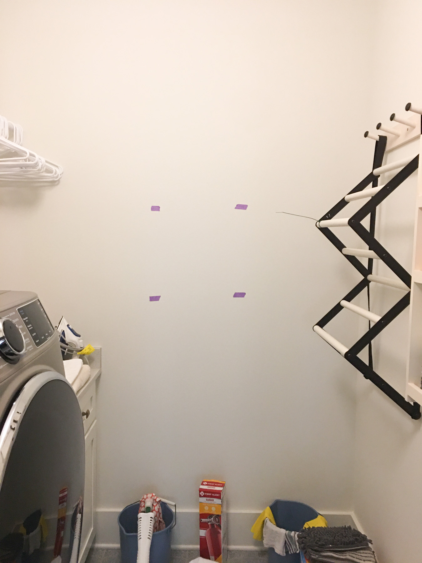 Before photo of a laundry room space with a taped out area on the wall for a new photograph