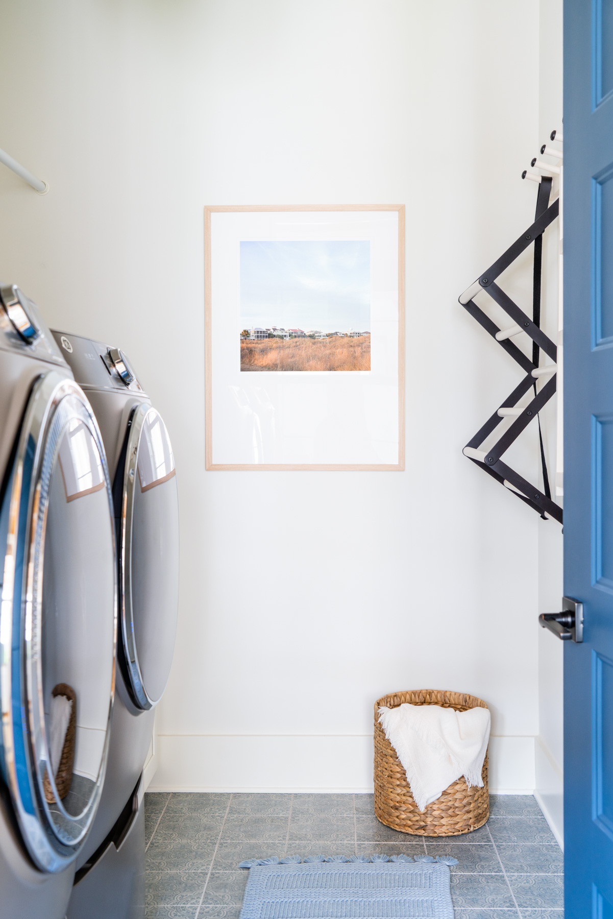 A light, spacious laundry room with a framed photo of beach houses on Sullivan's Island, South Carolina on the wall. 