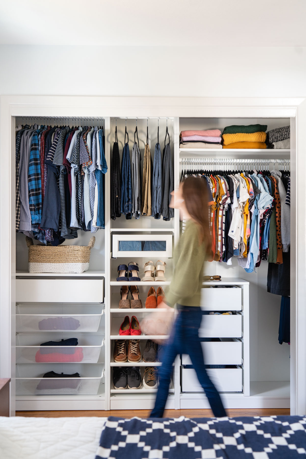A woman walking in front of her master bedroom closet designed with IKEA PAX wardrobe system