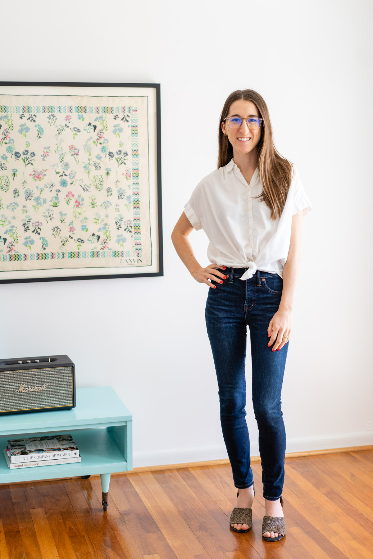 Woman modeling Madewell's dark Skinny jeans with a white button up shirt tied at the waist