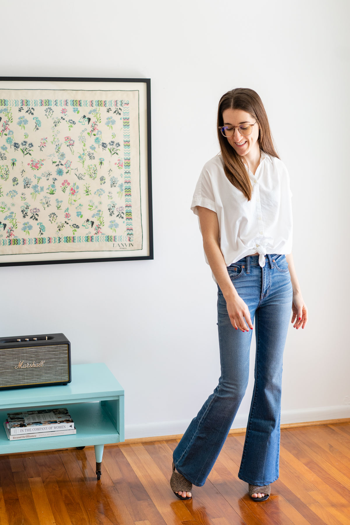 Woman modeling Madewell's Flare jeans with a white button up shirt tied at the waist