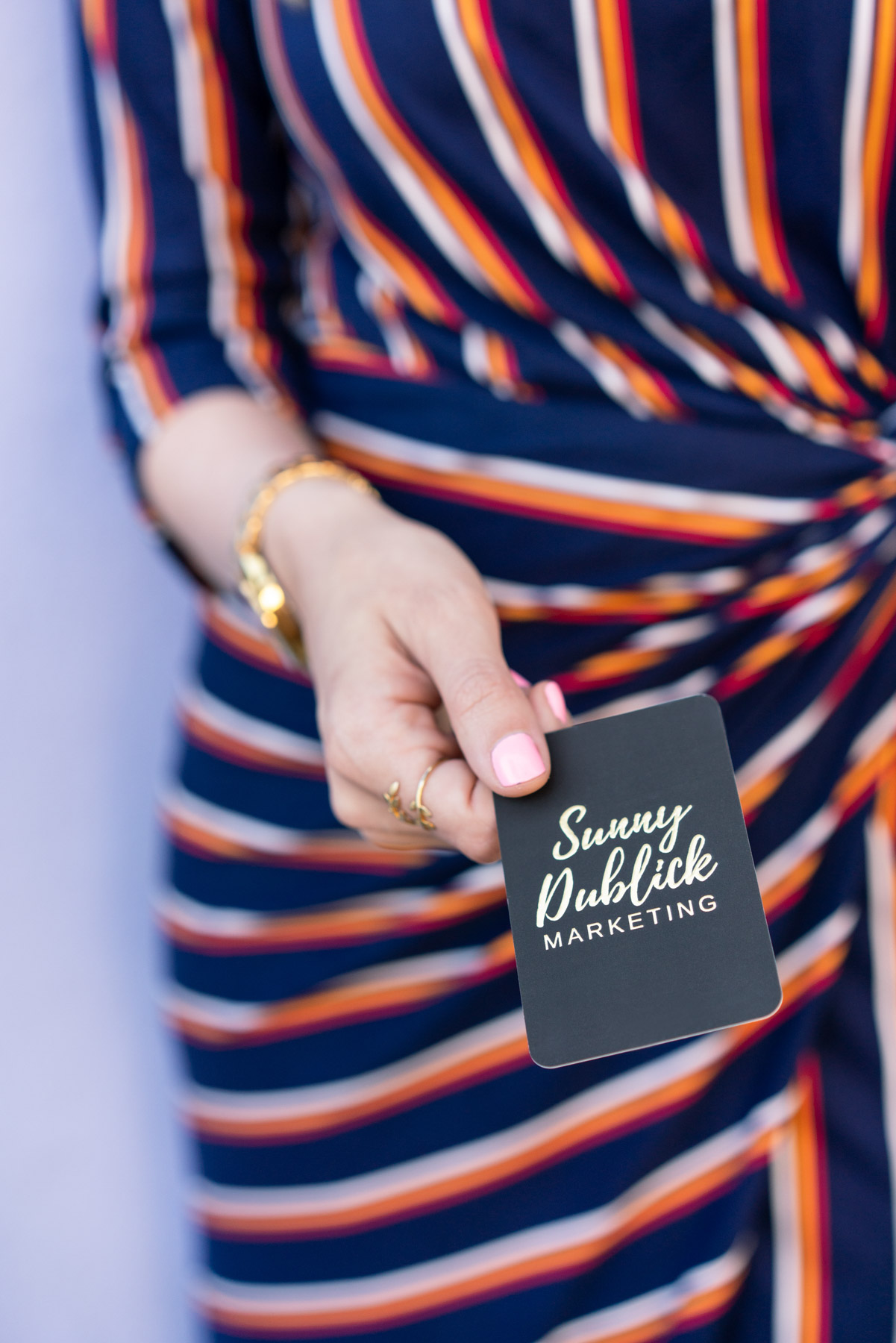 Small business brand photo of a woman holding out a business card for her marketing business