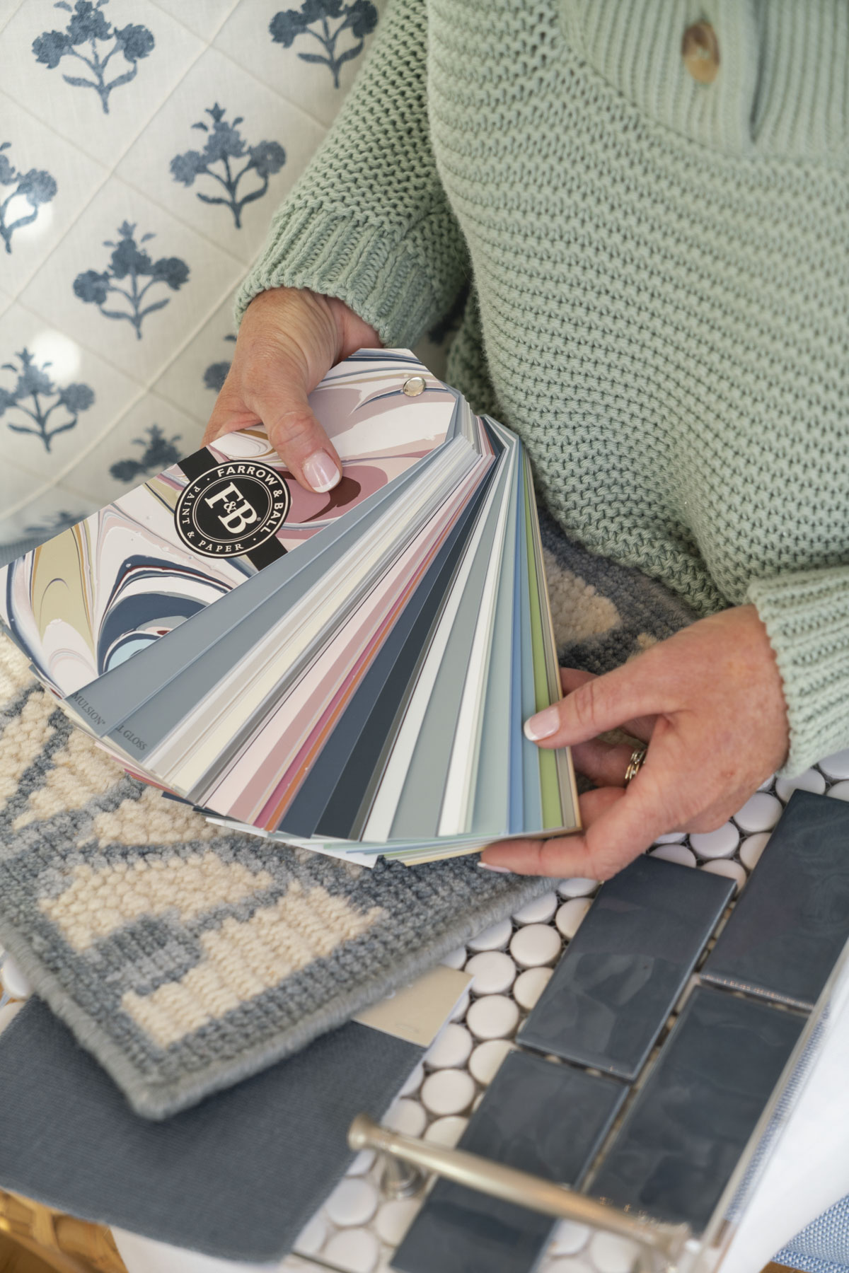 A pair of hands holding a fan of paint swatches 