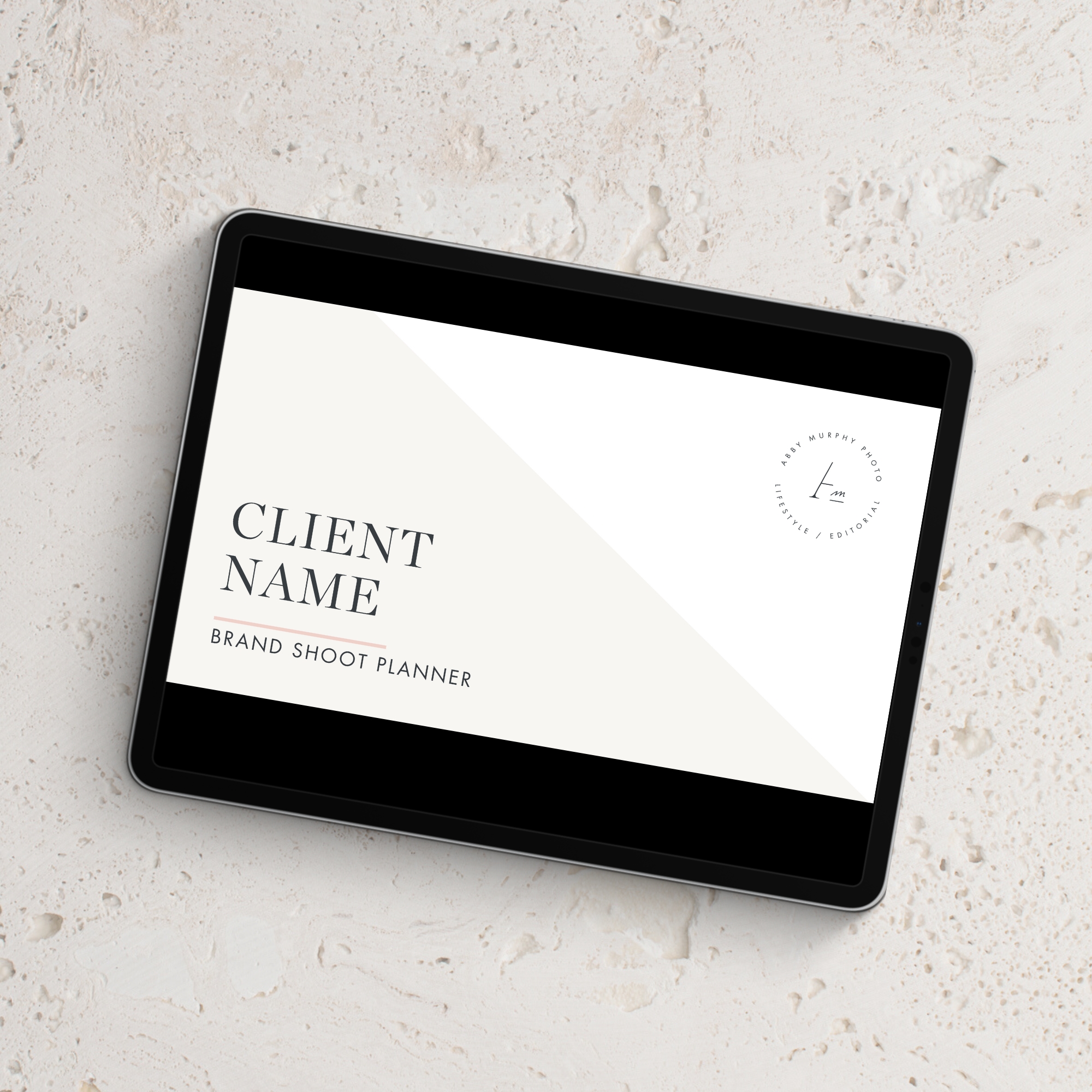 An iPad on a textured stone background with a brand photoshoot planner template on the screen.