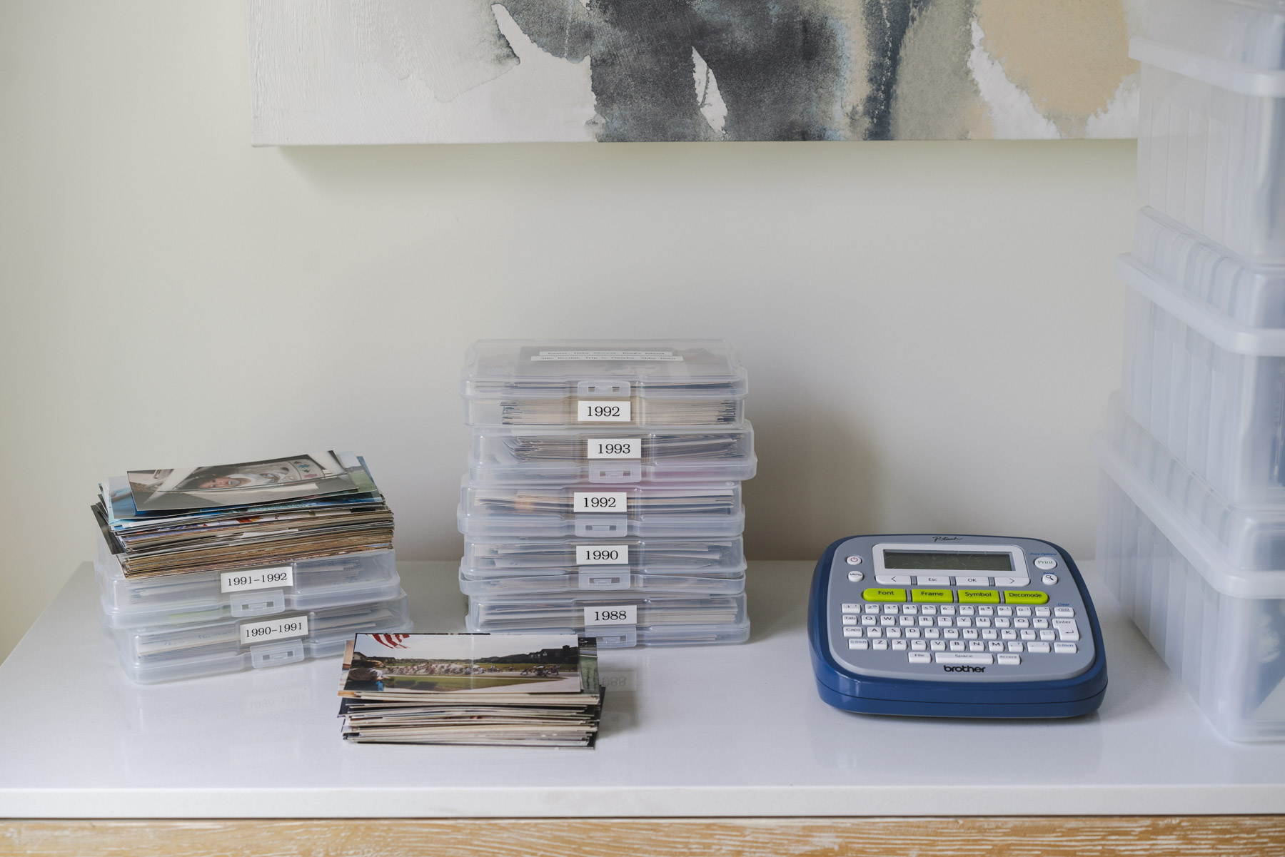 Photo of a stack of compartments of the Iris photo box. Next to that is a stack of photos. Next to that is a label maker. 
